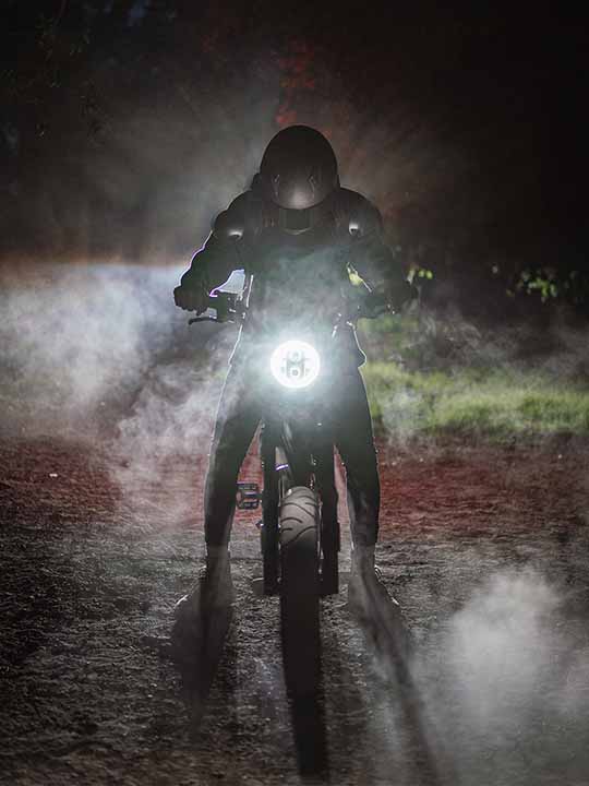 A motorcyclist rides at night, illuminated by a glowing dashboard light amidst a foggy, dark background.
AI-generated content may be incorrect.
